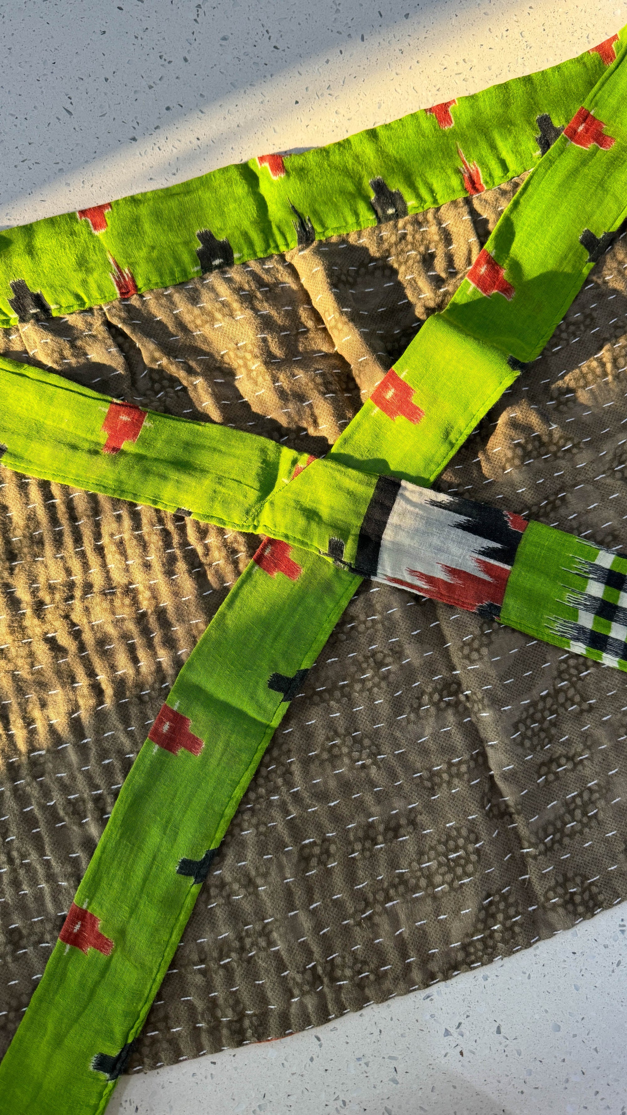 a green kite with red and white designs on it