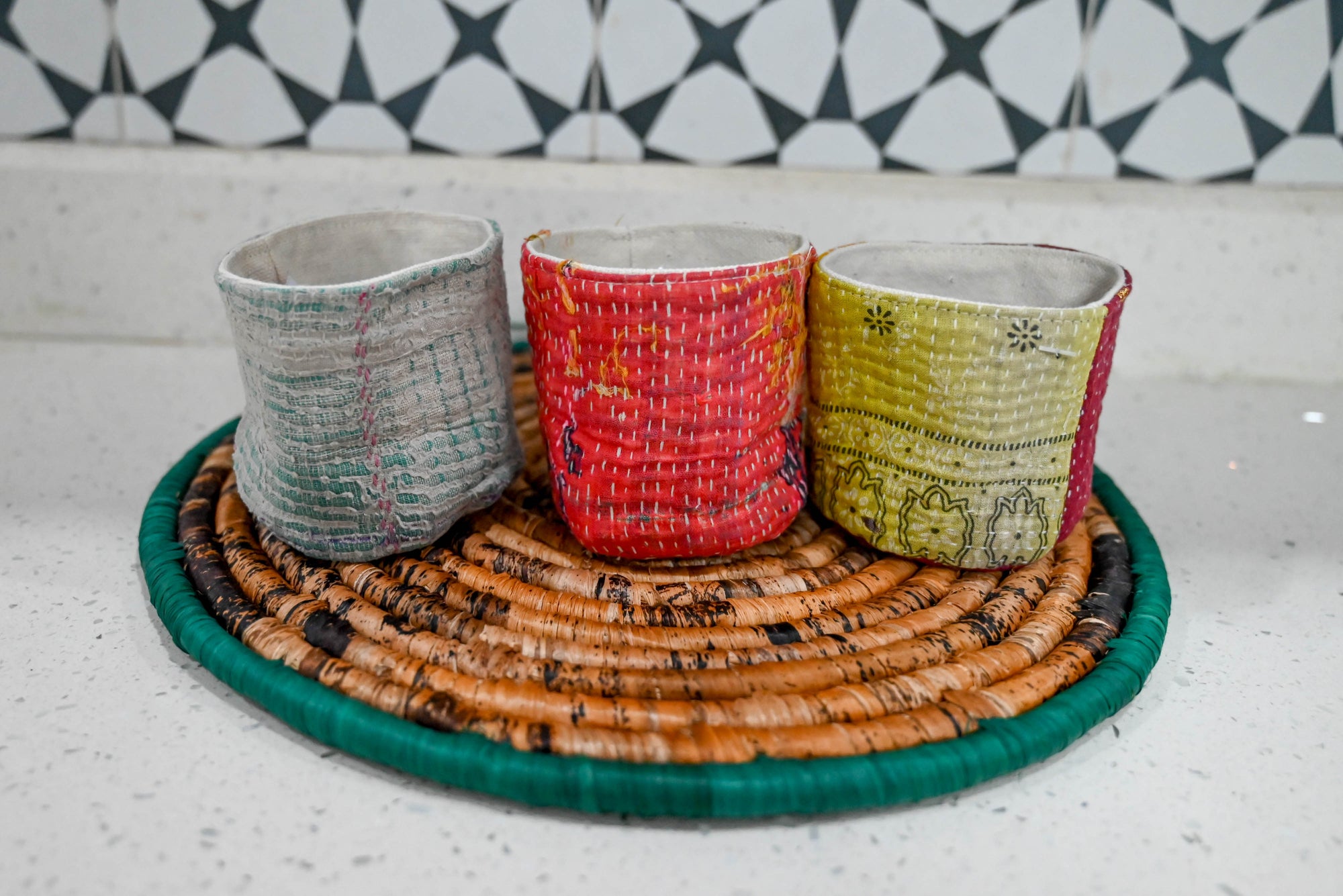 three different colored cups sitting on top of a wicker tray