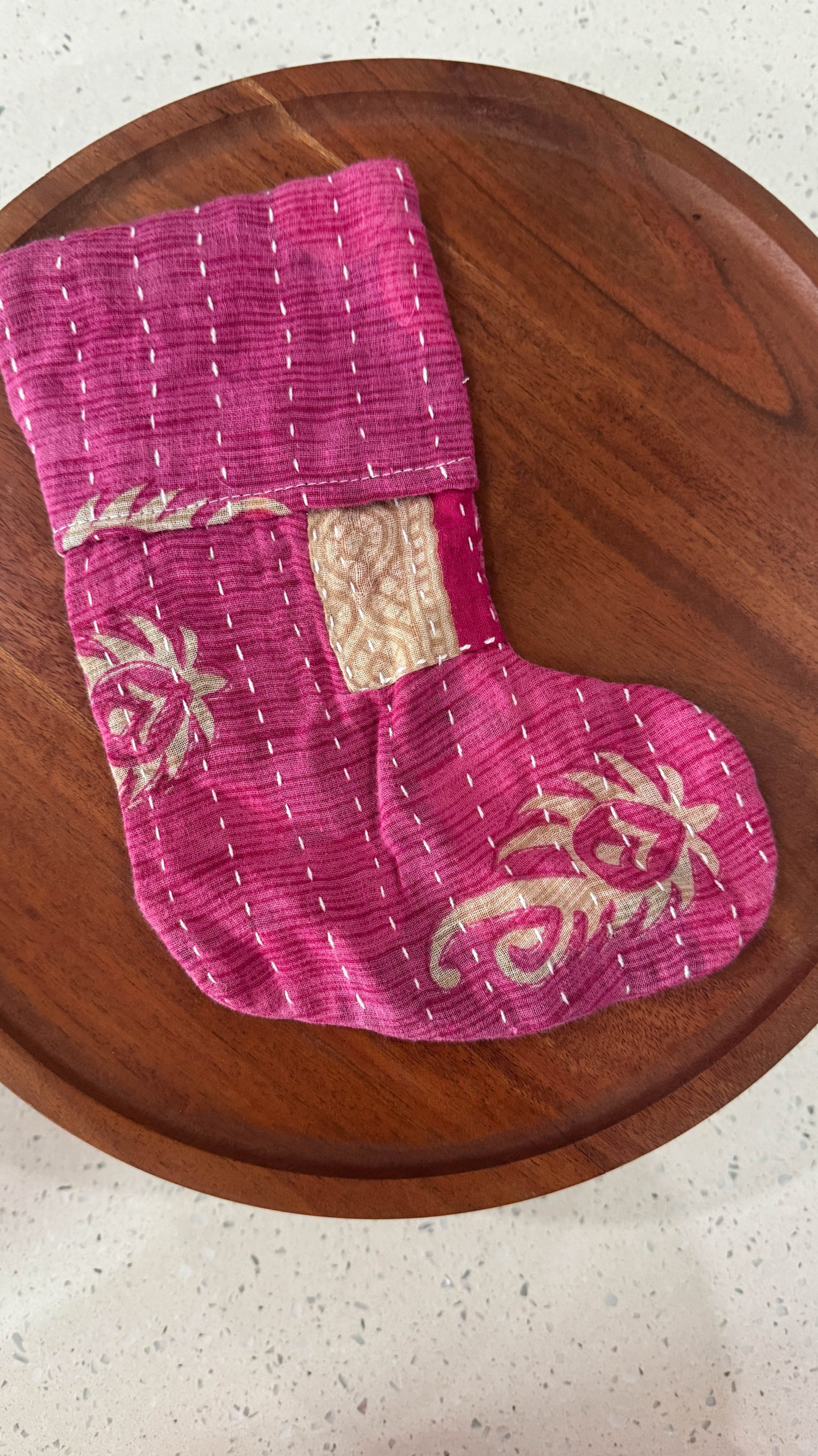 a wooden plate with a pink oven mitt on it