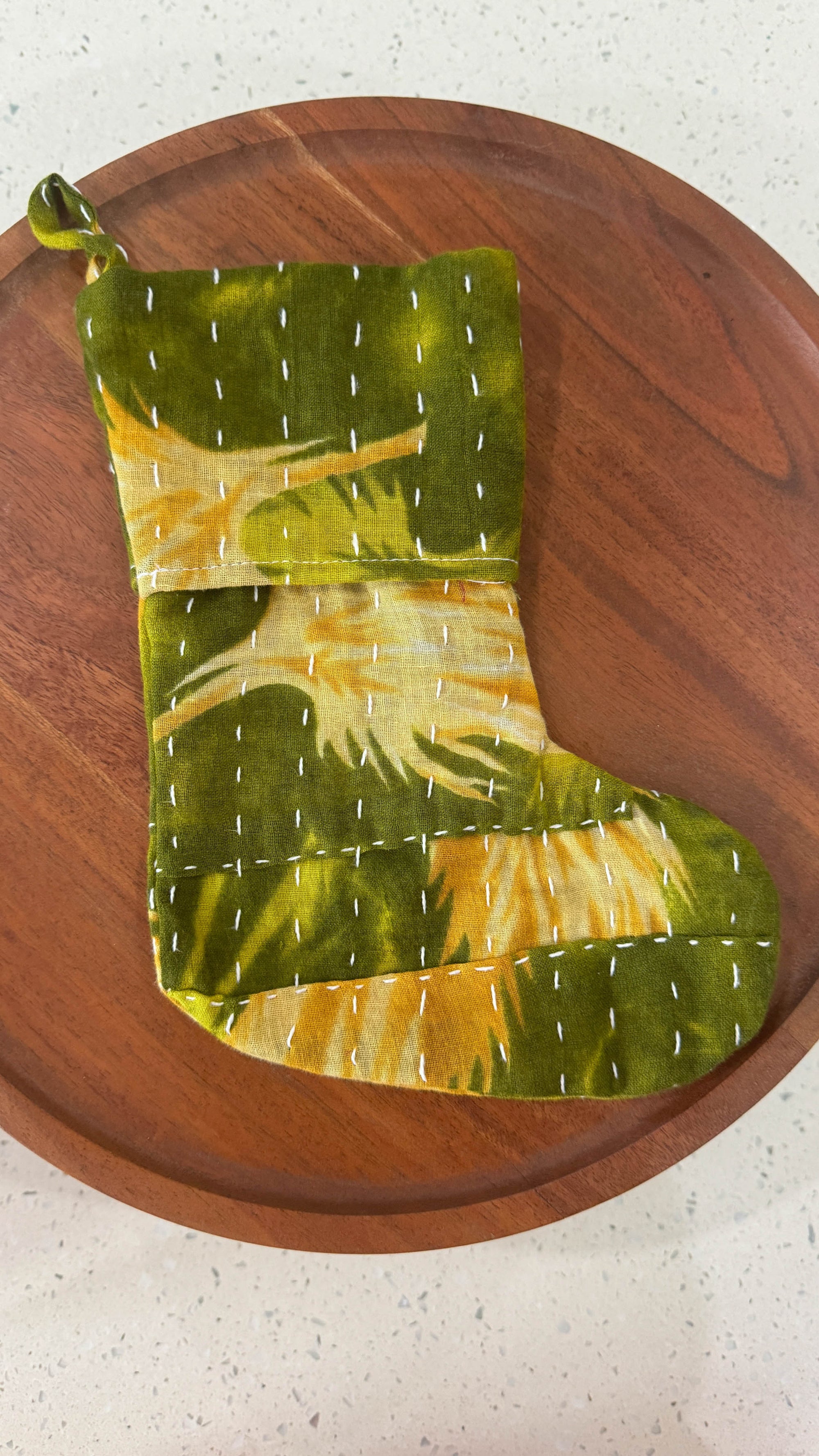 a green and yellow christmas stocking sitting on top of a wooden plate