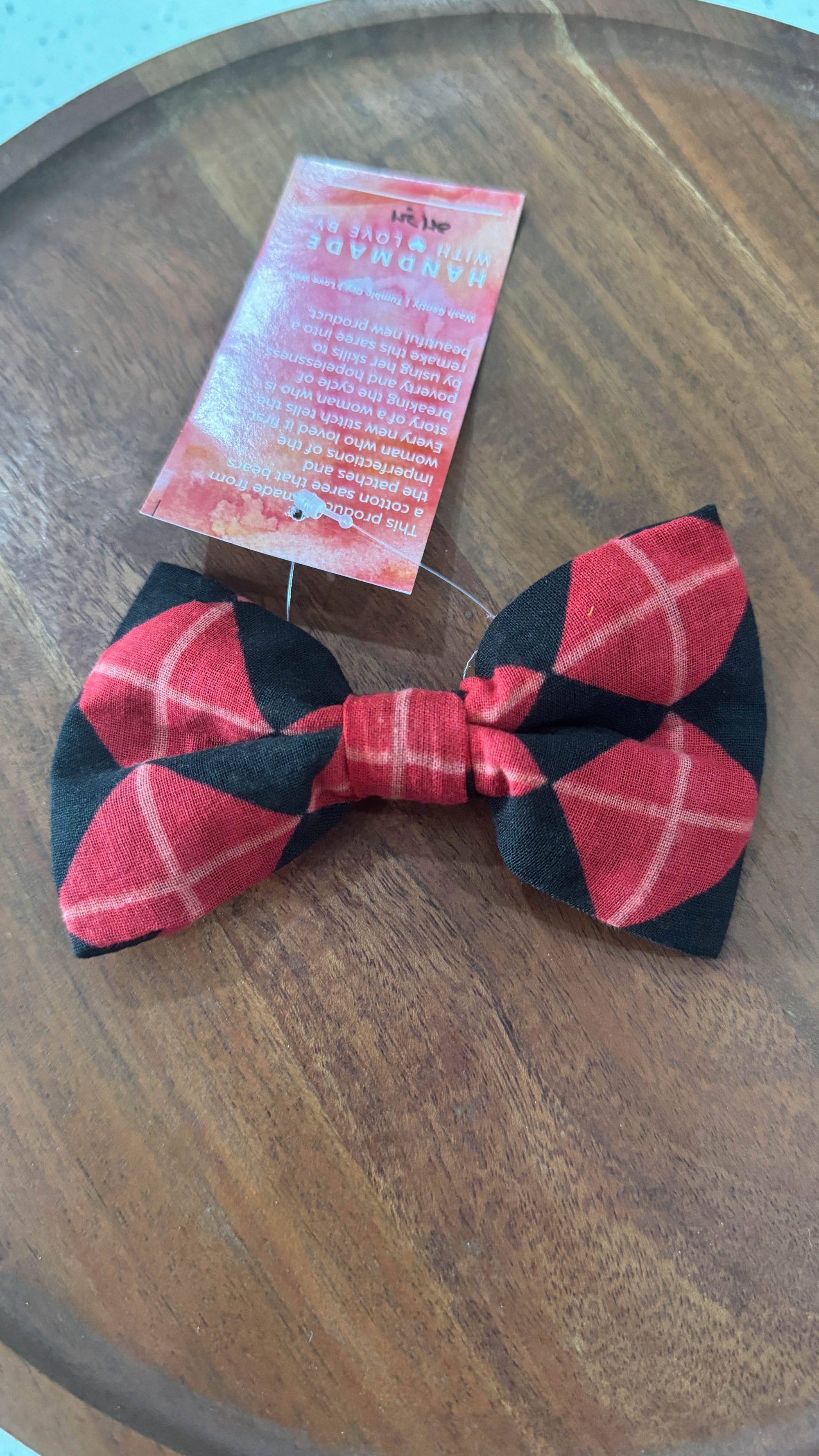 a red and black bow tie sitting on top of a wooden table