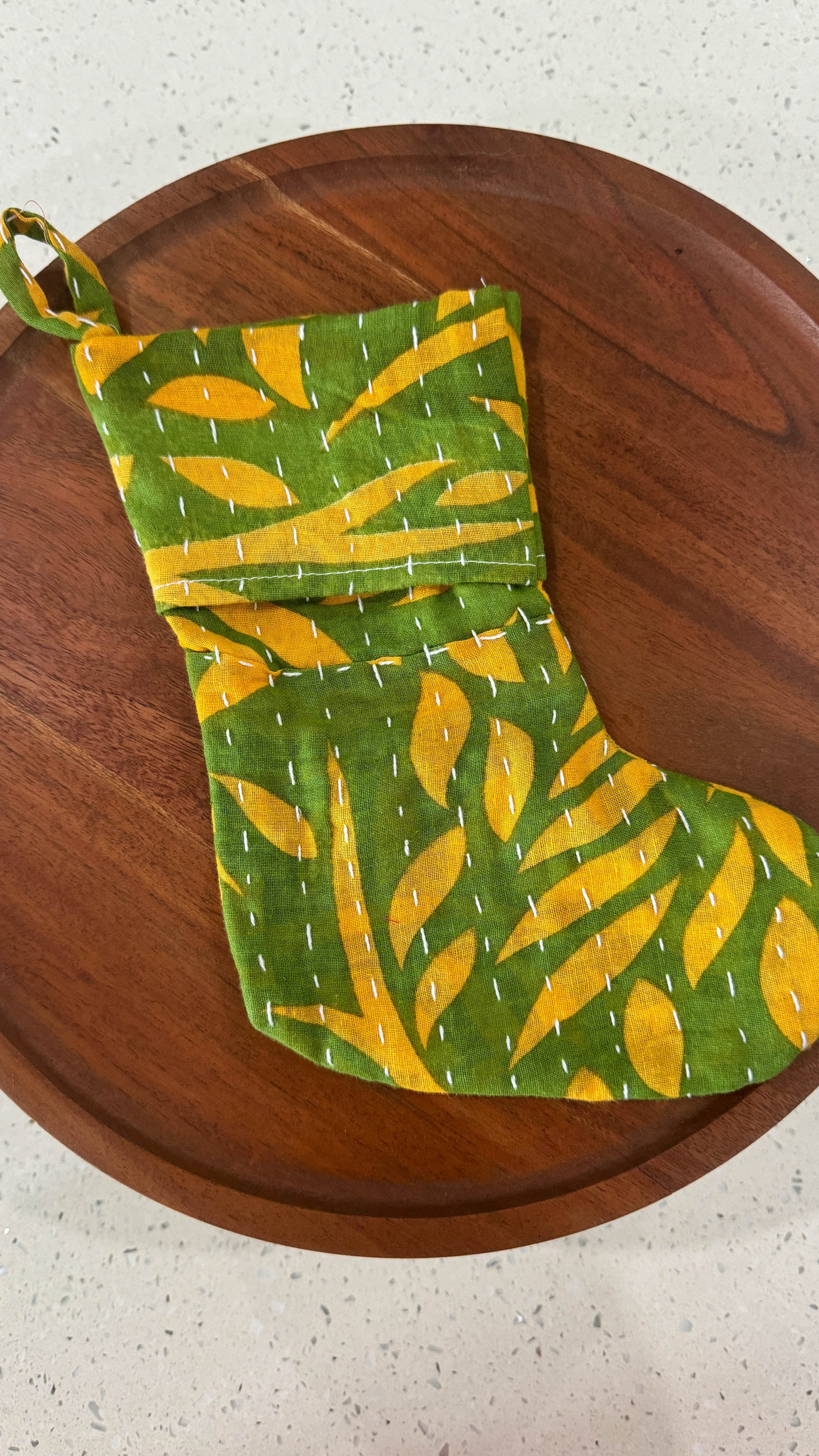 a green and yellow oven mitt on a wooden tray