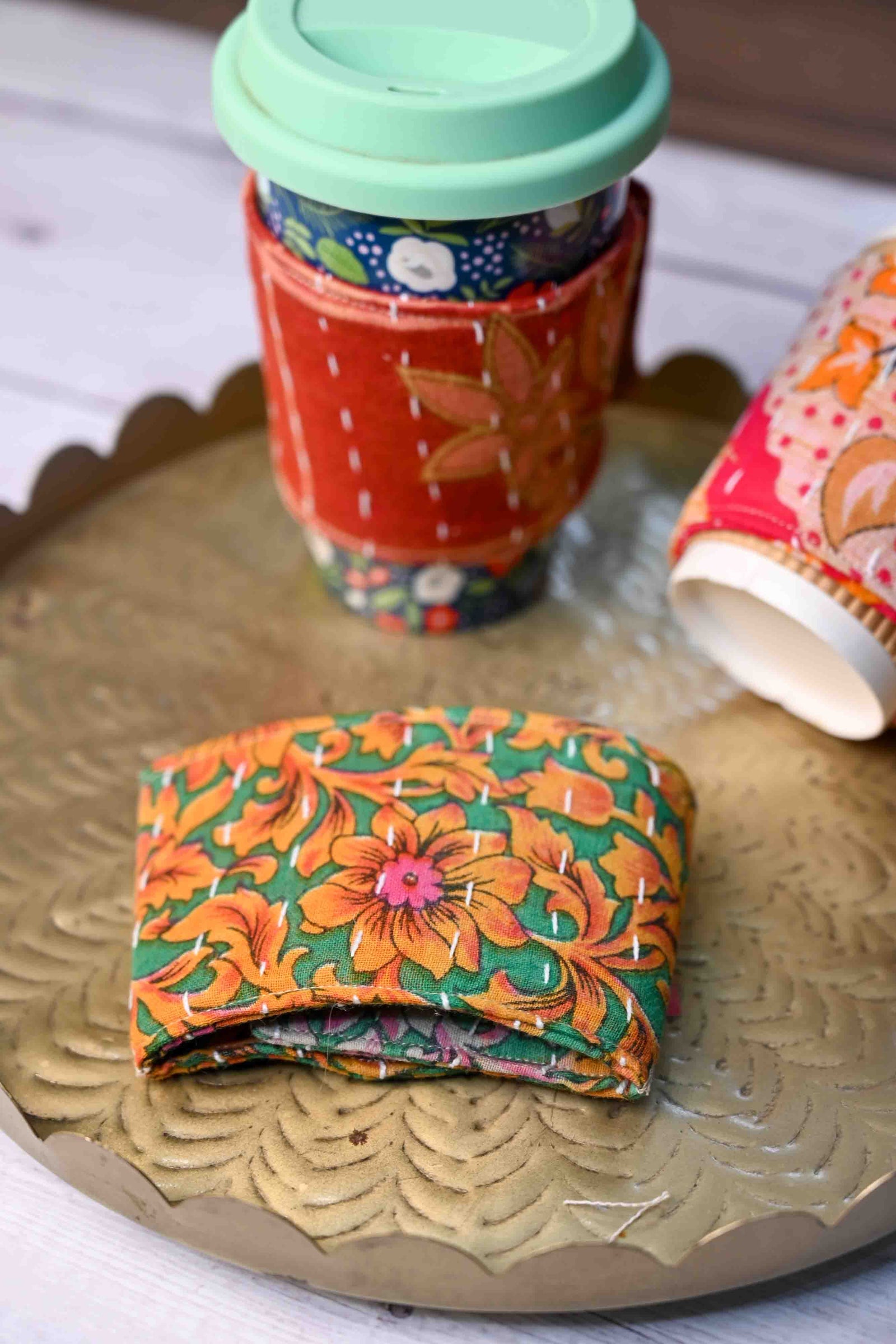 Kantha coffee cozy featuring colorful, hand-stitched patterns, designed to wrap around your cup and protect your hands from both heat and cold.