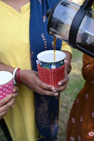 Kantha coffee cozy featuring colorful, hand-stitched patterns, designed to wrap around your cup and protect your hands from both heat and cold.