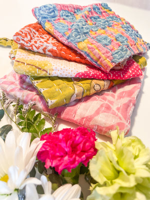 A vibrant, hand-stitched Kantha dish cloth featuring a colorful design. The cloth is made from soft, lightweight recycled saree fabric with intricate running stitches creating a textured pattern. The colors of fresh spring meadow add a playful and rustic touch to kitchen cleaning essentials.