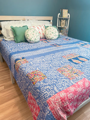 A beautiful Hope Quilt made from recycled sarees, featuring intricate Kantha stitching. This vibrant quilt, designed to fit a full/queen bed, showcases a patchwork of colorful fabric pieces, each carefully hand-stitched together. The delicate Kantha stitching adds texture and depth, creating a warm, sustainable, and artistic piece for your bed.