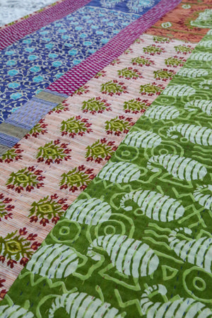 A beautiful Hope Quilt made from recycled sarees, featuring intricate Kantha stitching. This vibrant quilt, designed to fit a full/queen bed, showcases a patchwork of colorful fabric pieces, each carefully hand-stitched together. The delicate Kantha stitching adds texture and depth, creating a warm, sustainable, and artistic piece for your bed.