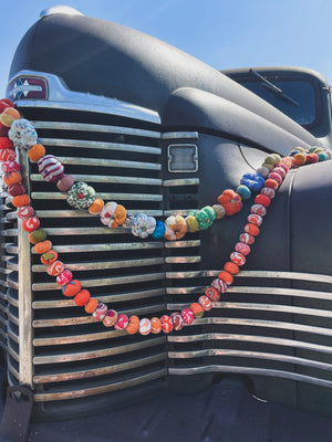 A variety of colorful handmade pumpkin-shaped garlands made from recycled saree material, displayed on a white background.