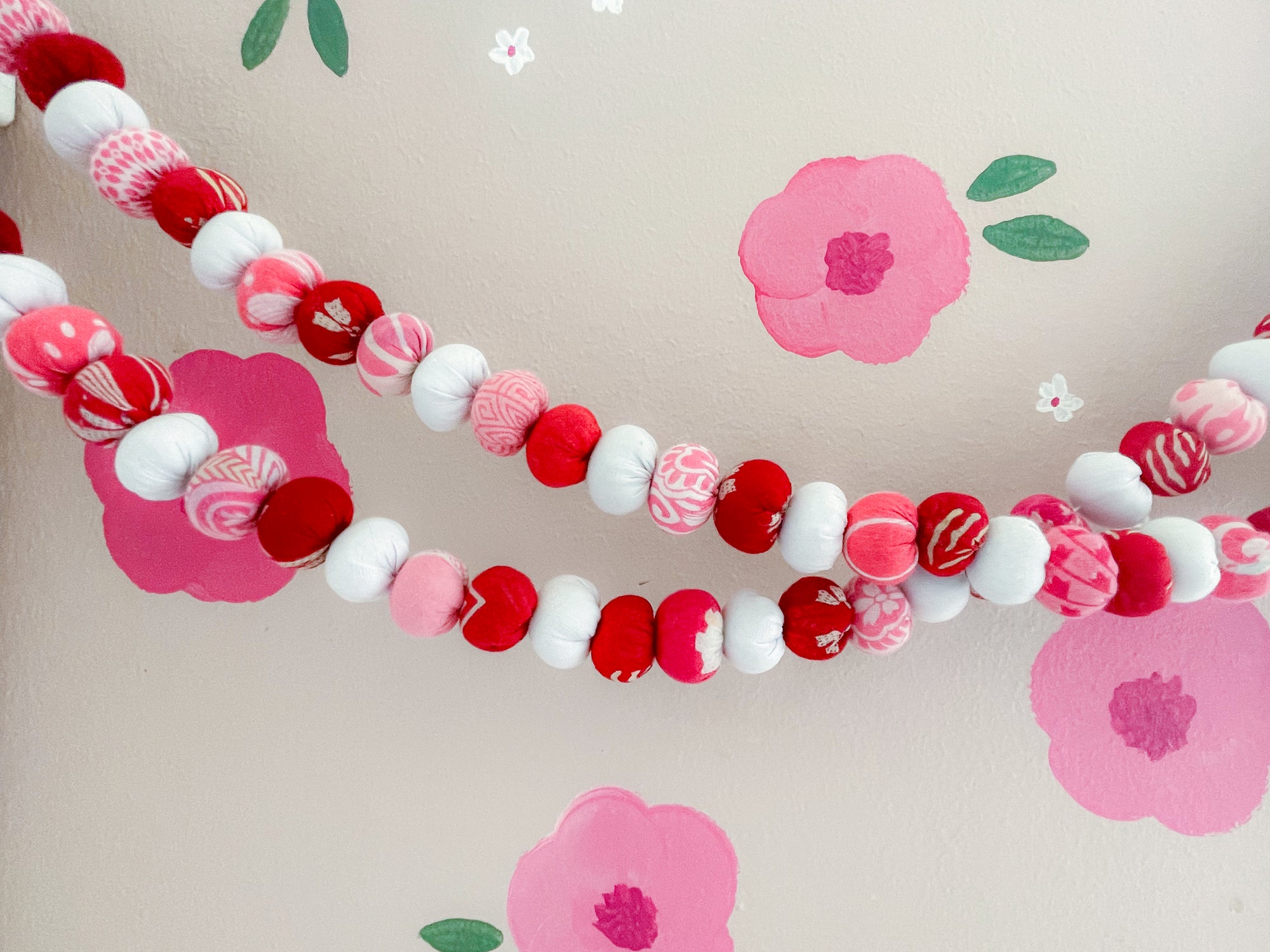 Handmade Valentine’s bead garland featuring a mix of red, pink, and white beads, crafted from recycled saree scraps, perfect for adding a festive and eco-friendly touch to your Valentine’s Day decor.