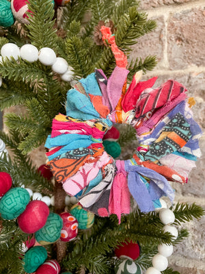 Vibrant Saree Sunburst Ornament, made from colorful saree scraps hand-tied to a ring, creating a bright and beautiful decorative piece perfect for adding a festive touch to your Christmas tree.