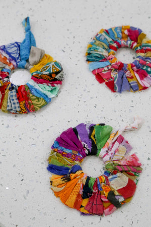 Vibrant Saree Sunburst Ornament, made from colorful saree scraps hand-tied to a ring, creating a bright and beautiful decorative piece perfect for adding a festive touch to your Christmas tree