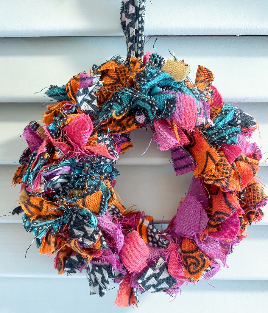 Small saree wreath ornament made from colorful hand tied saree fabric scraps, perfect for adding a vibrant and eco-friendly touch to holiday or home decor.