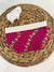 a pink and white purse sitting on top of a wicker basket
