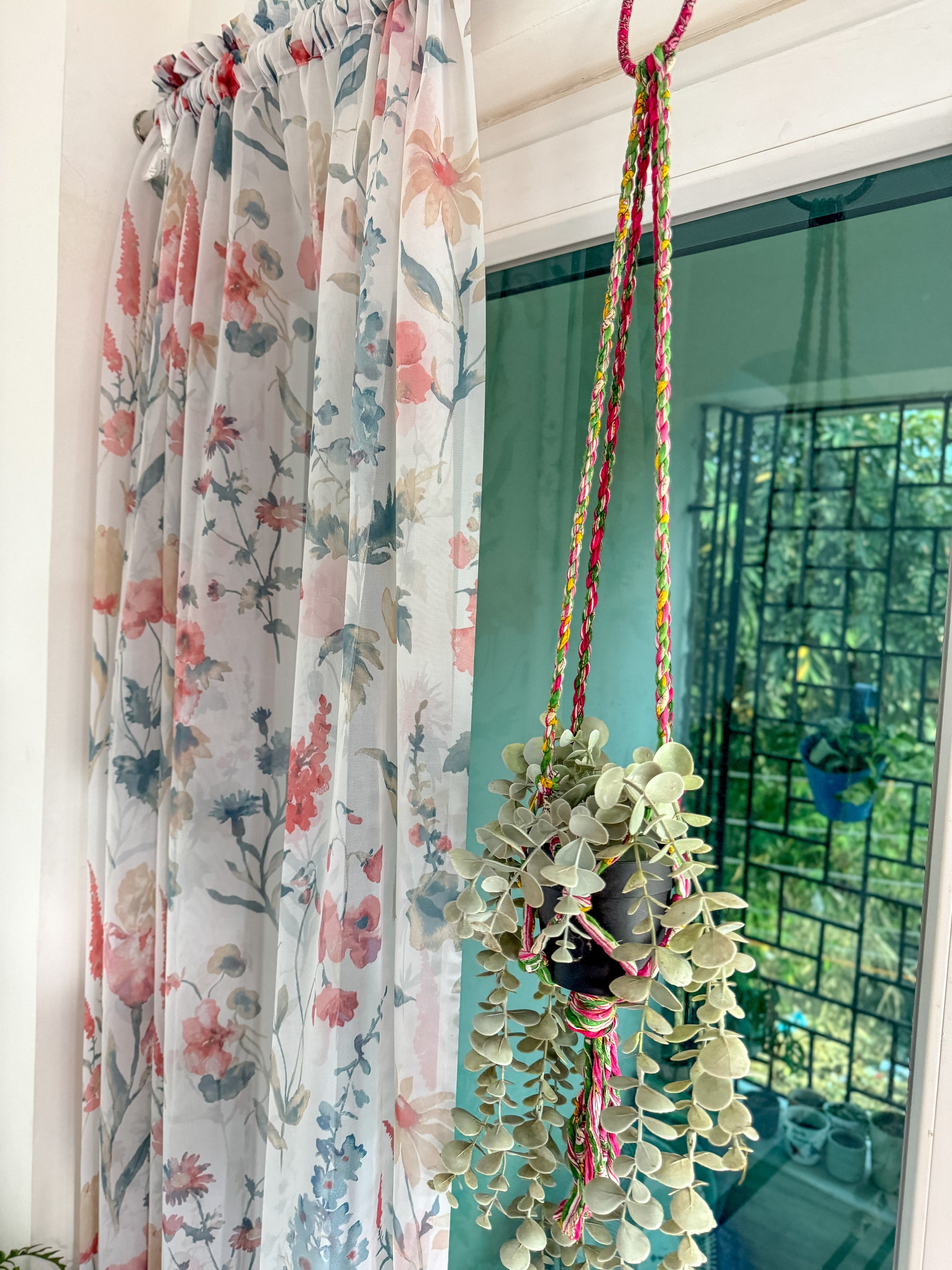 a window with a flowered curtain hanging from it's side