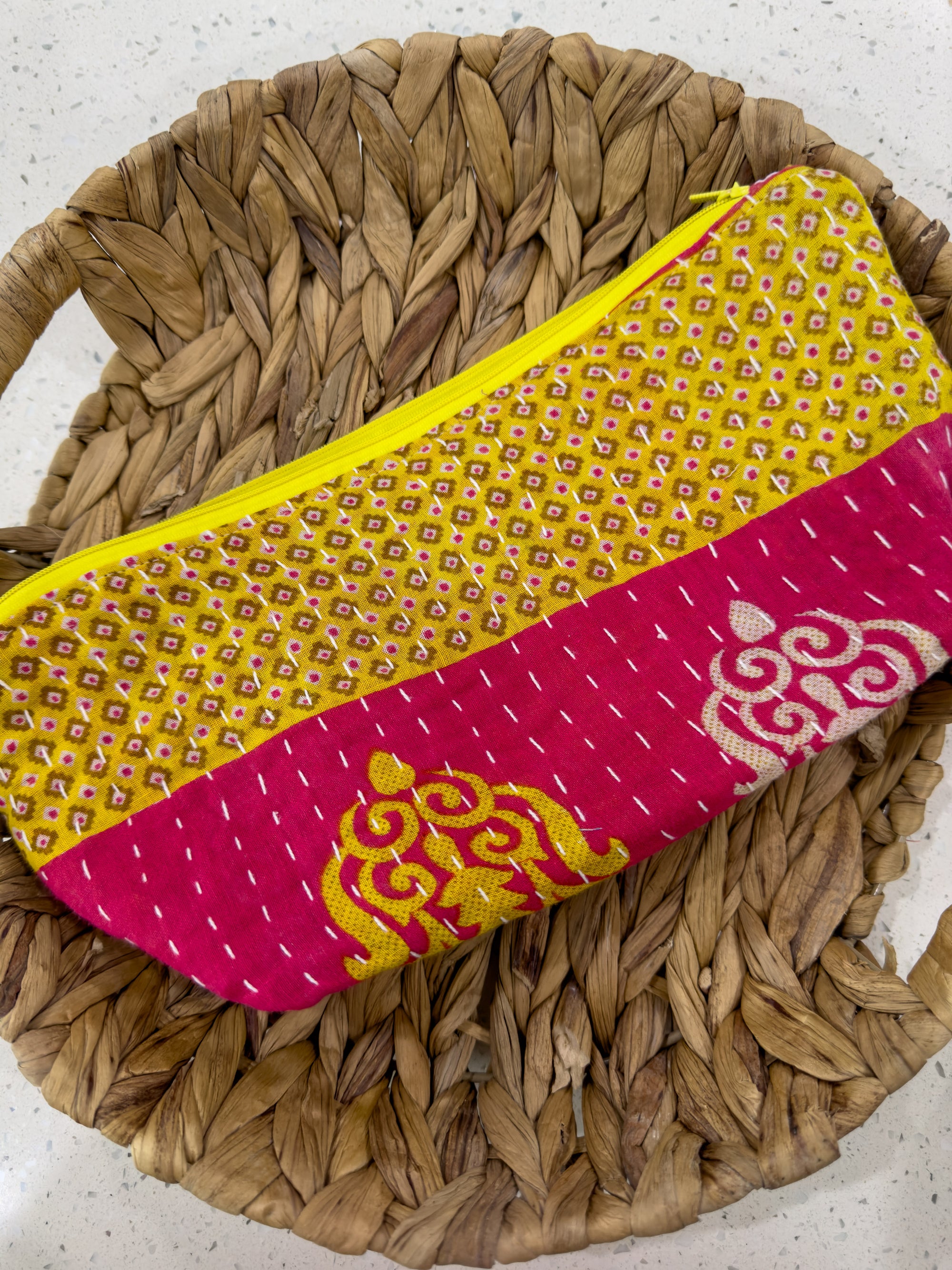 a yellow and pink bag sitting on top of a woven basket