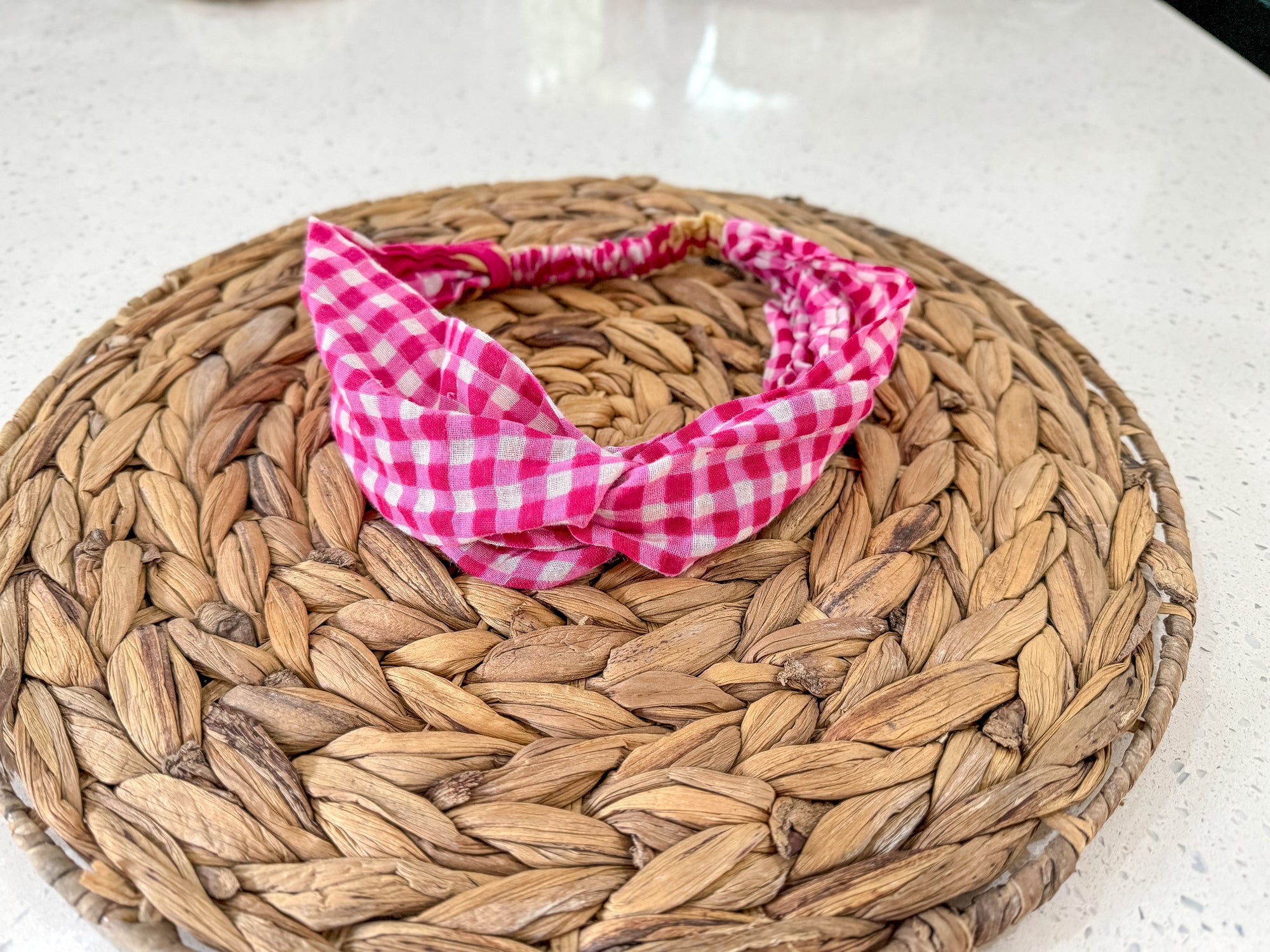 a pink and white checkered bandana sitting on top of a woven basket