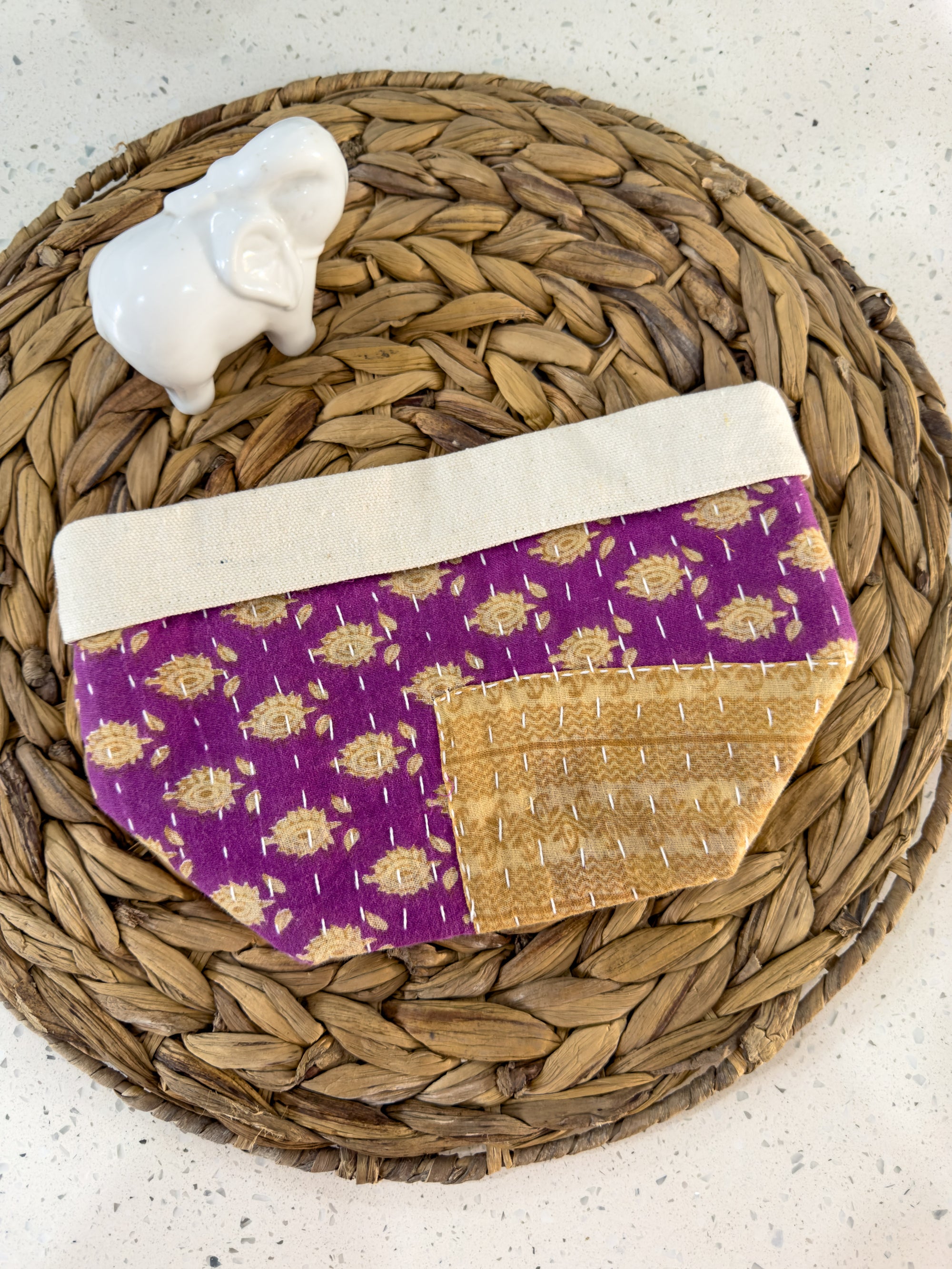 a purple and gold purse sitting on top of a wicker basket