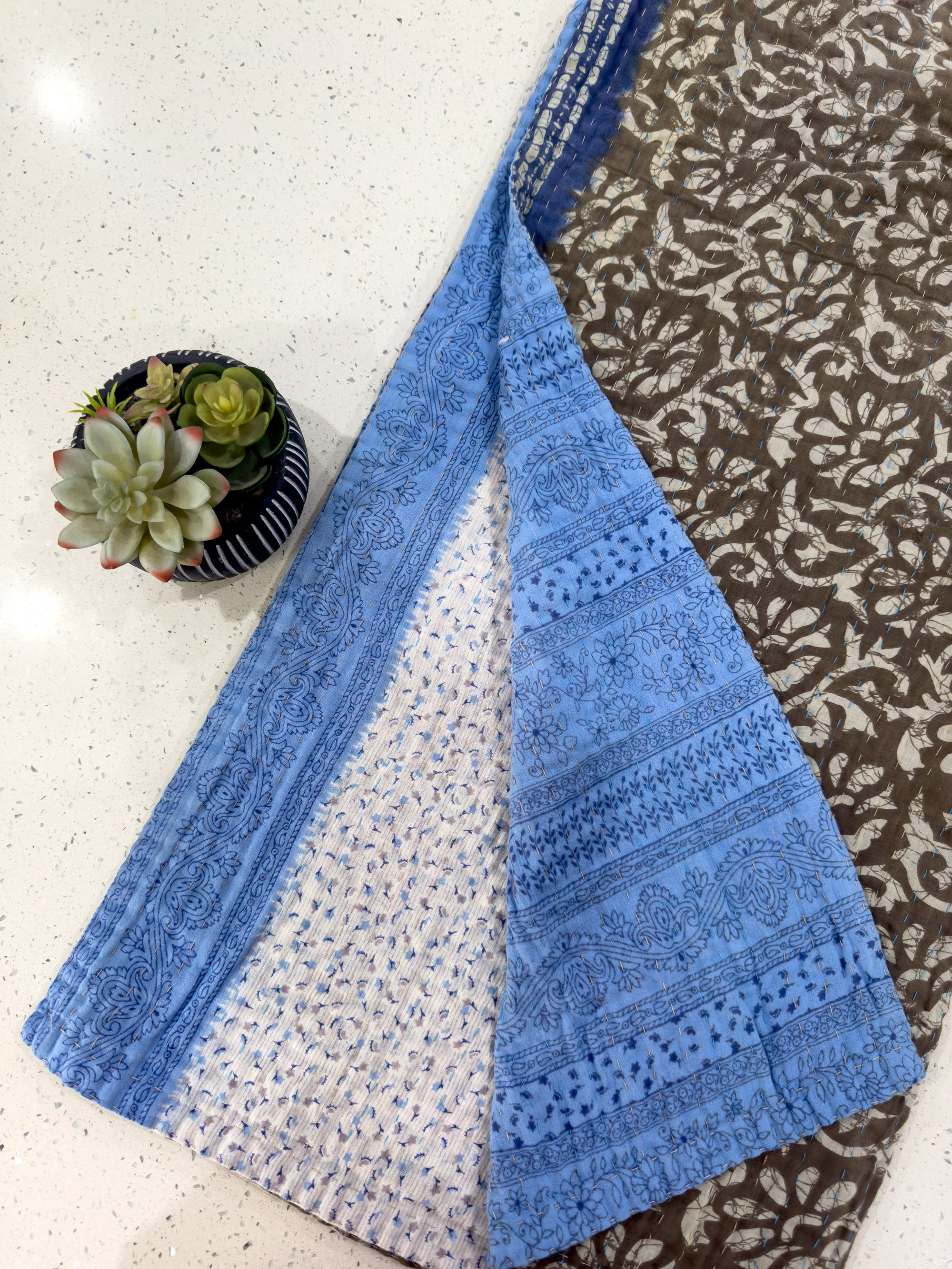 three pieces of blue and brown fabric next to a potted plant