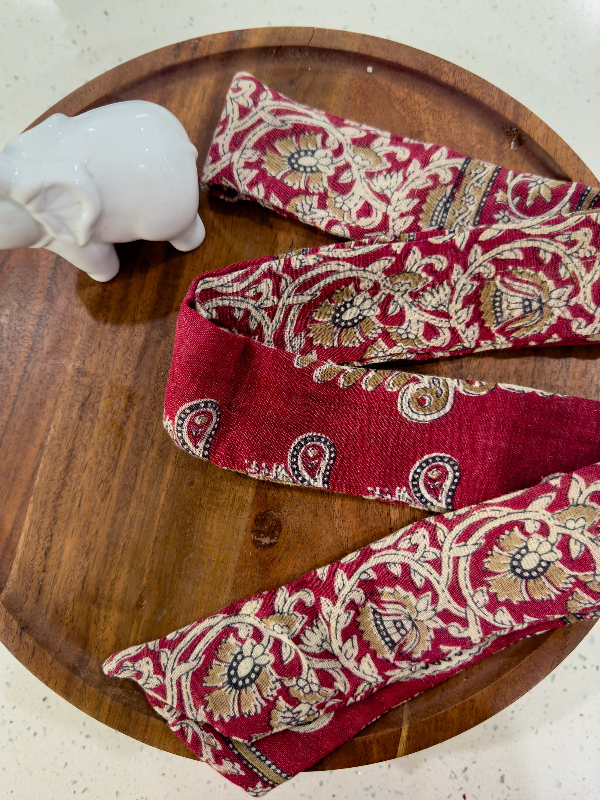 a pair of red paisley ties sitting on top of a wooden plate