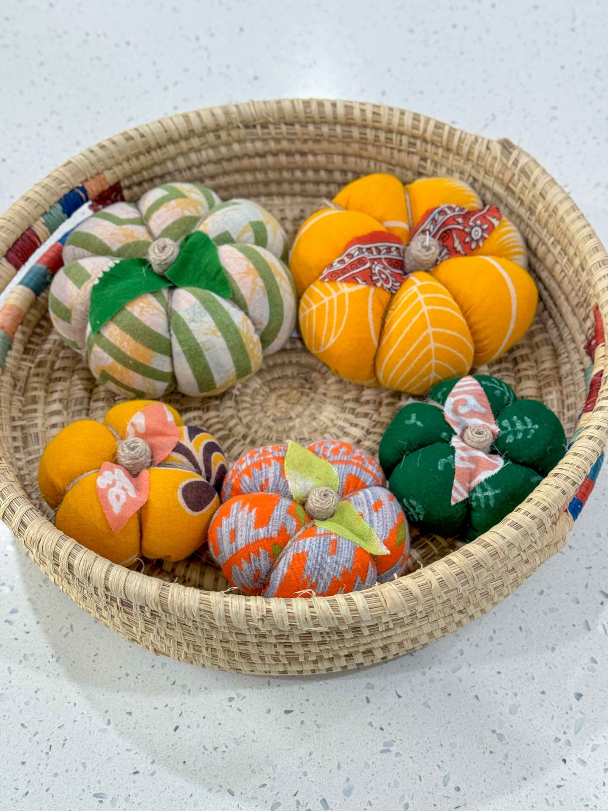 a wicker basket filled with small decorative pumpkins