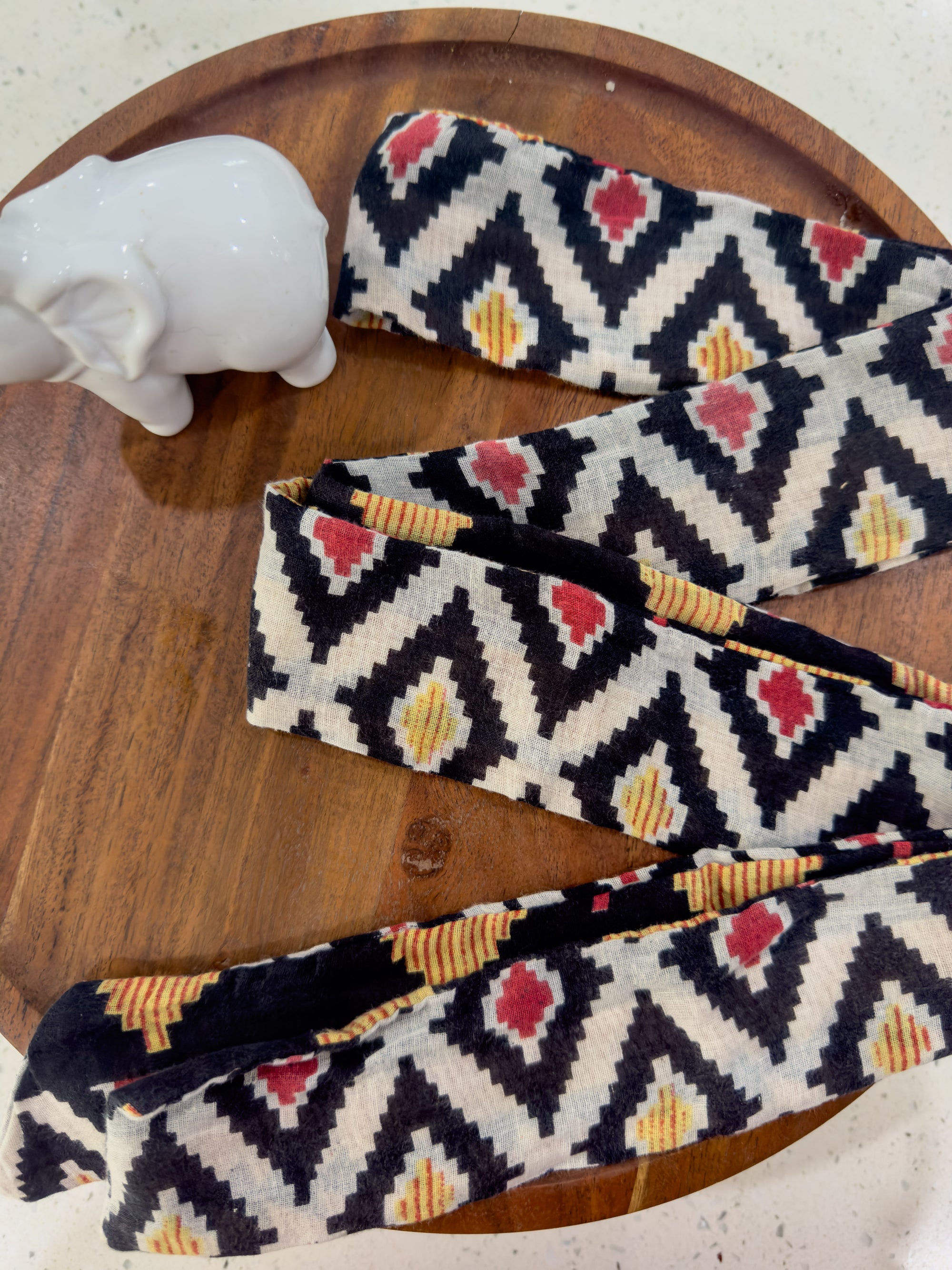 a pair of black, white, and red patterned ties on a wooden tray