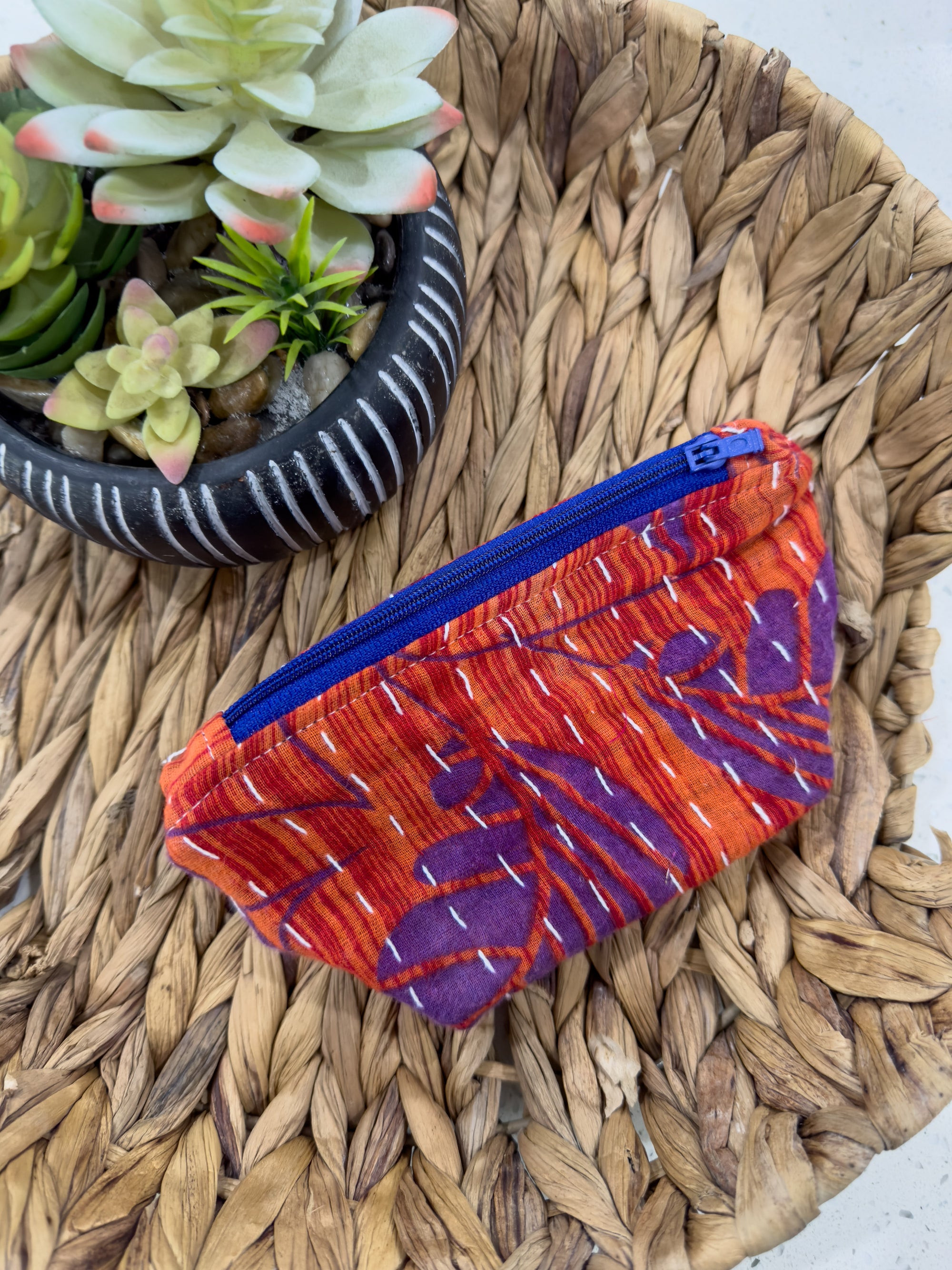 a small purse sitting on top of a table next to a potted plant