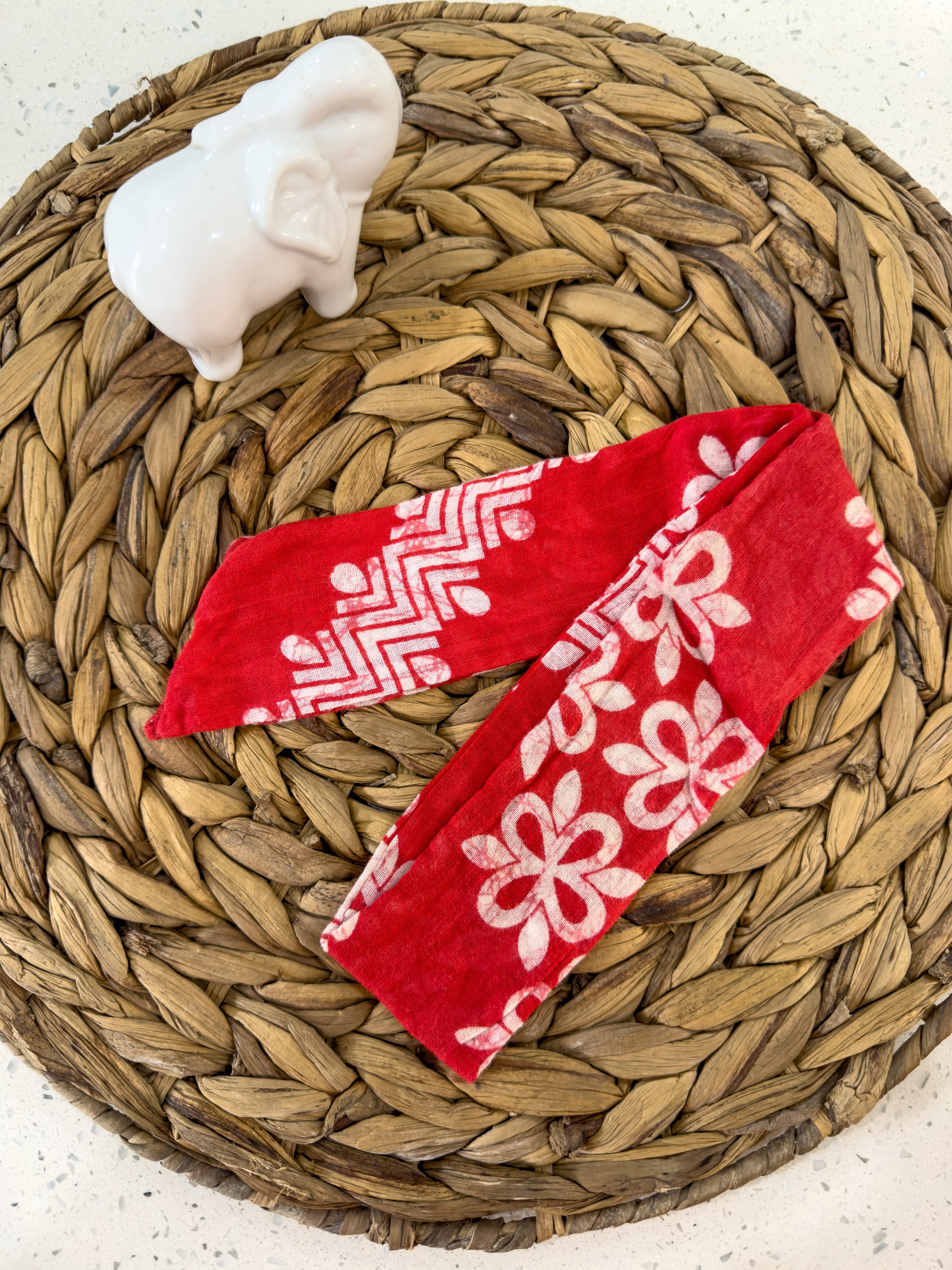 a basket with two red towels and a white elephant figurine