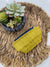 a yellow purse sitting on top of a table next to a potted plant