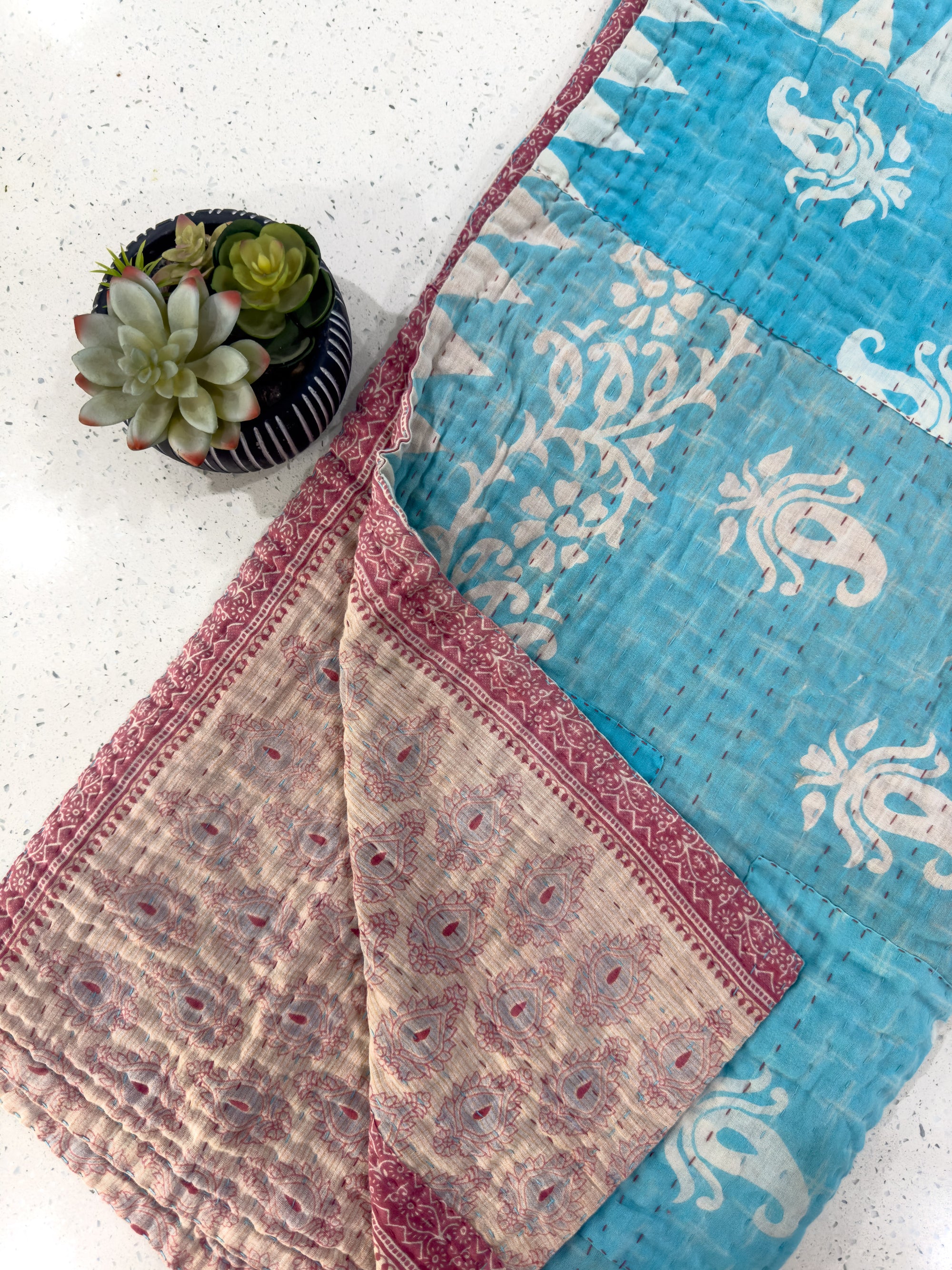 a potted plant sitting on top of a blue and pink quilt