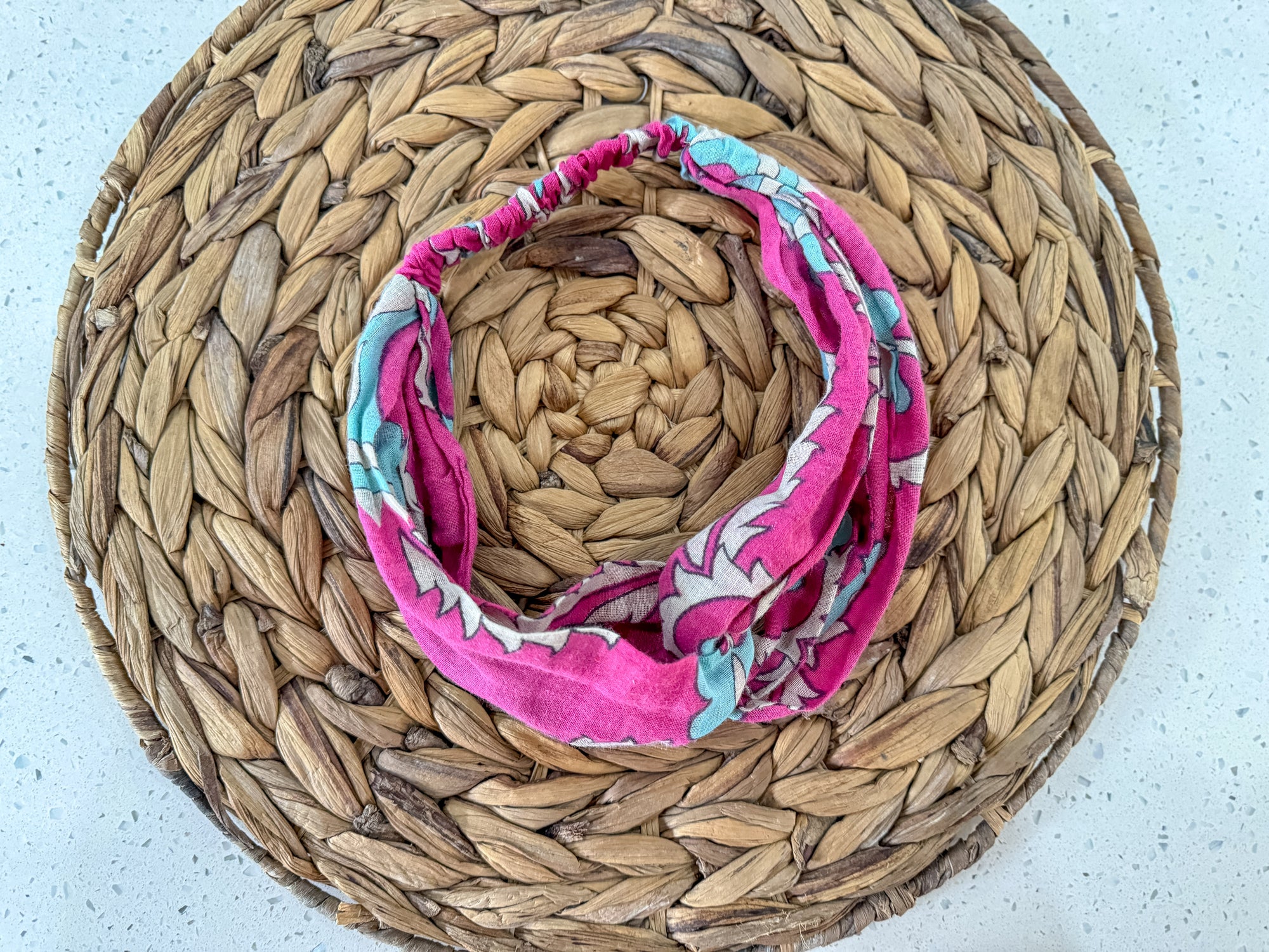 a woven basket with a pink scarf on top of it