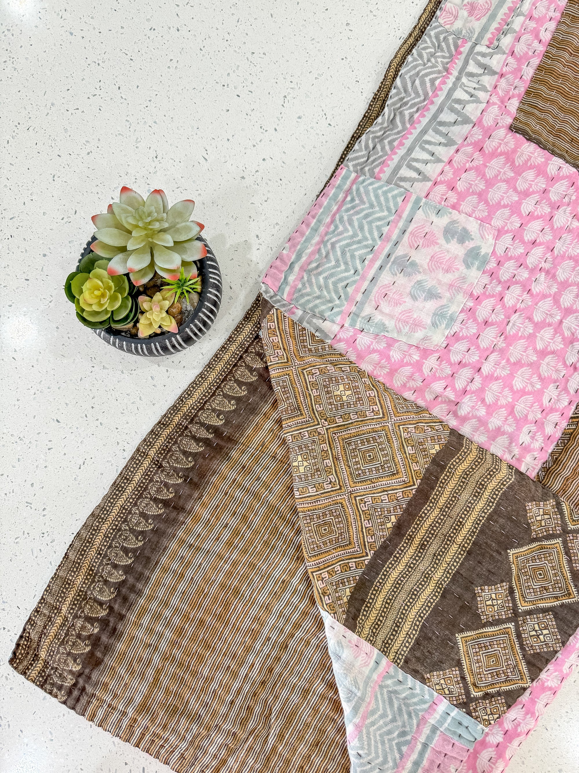 a potted plant sitting on top of a table next to a patchwork quilt